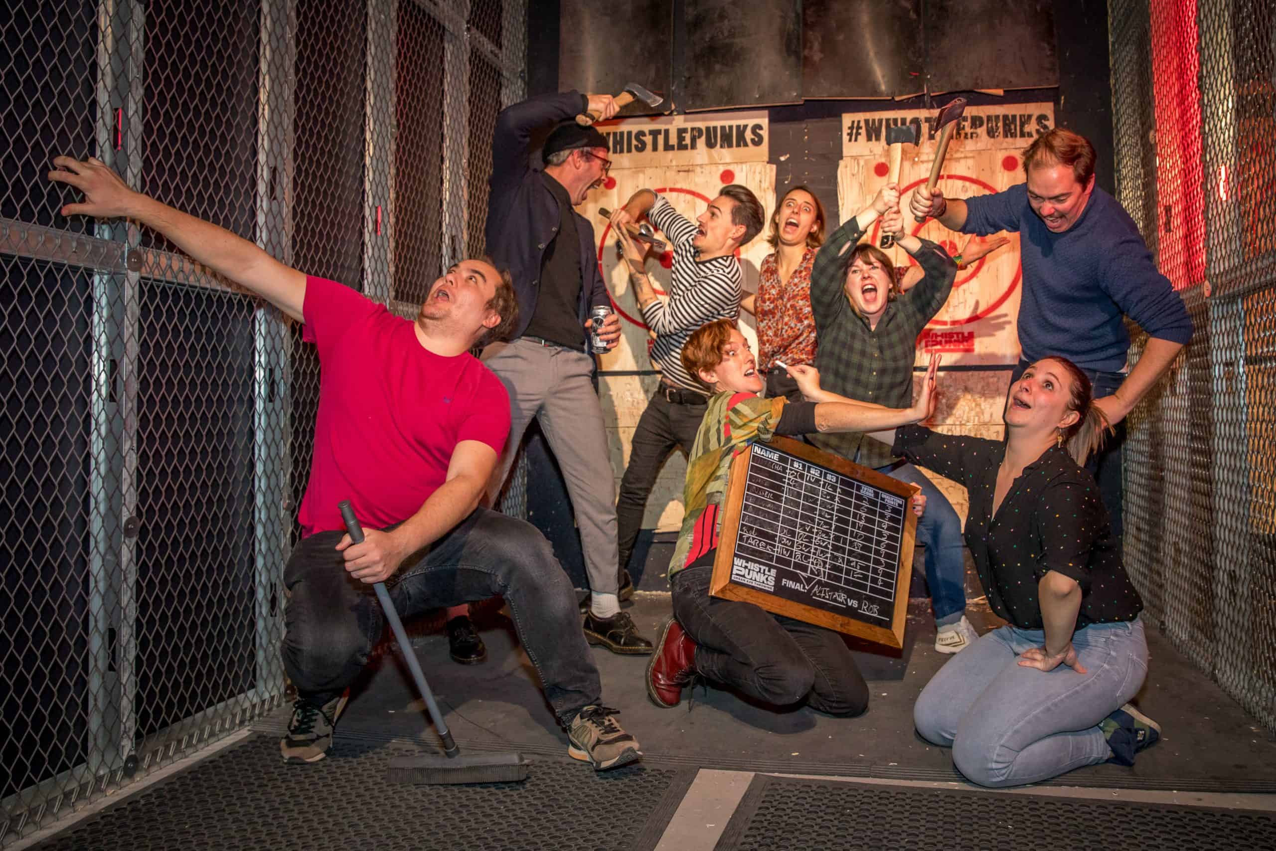 Group posing comically with axe throwing scoreboard