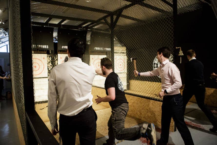 men in smart attire throwing axes